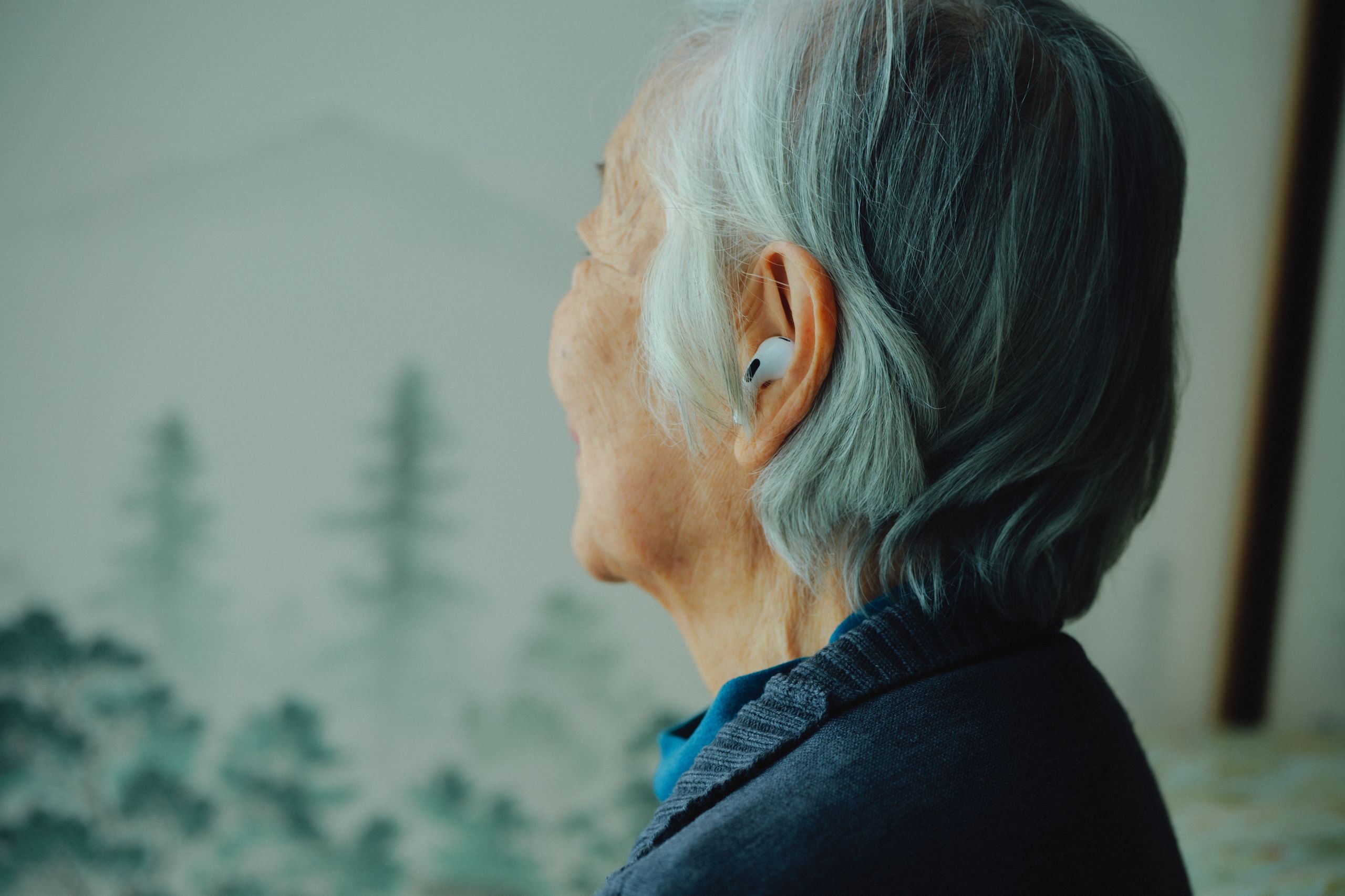 An older woman wearing an AirPod while testing its hearing-aid feature