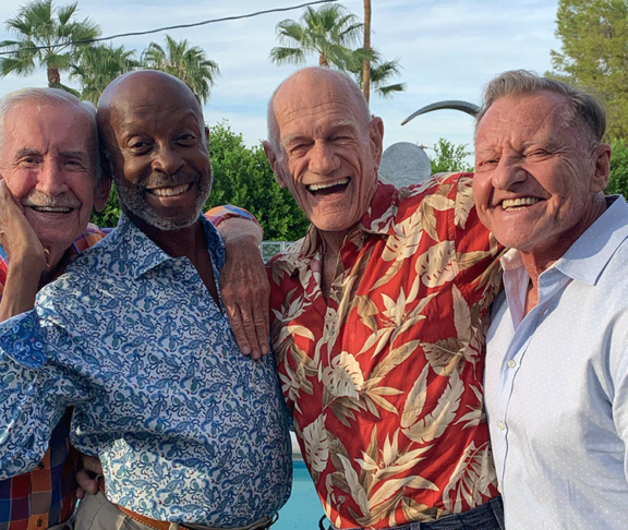 The Old Gays laughing together beside a swimming pool